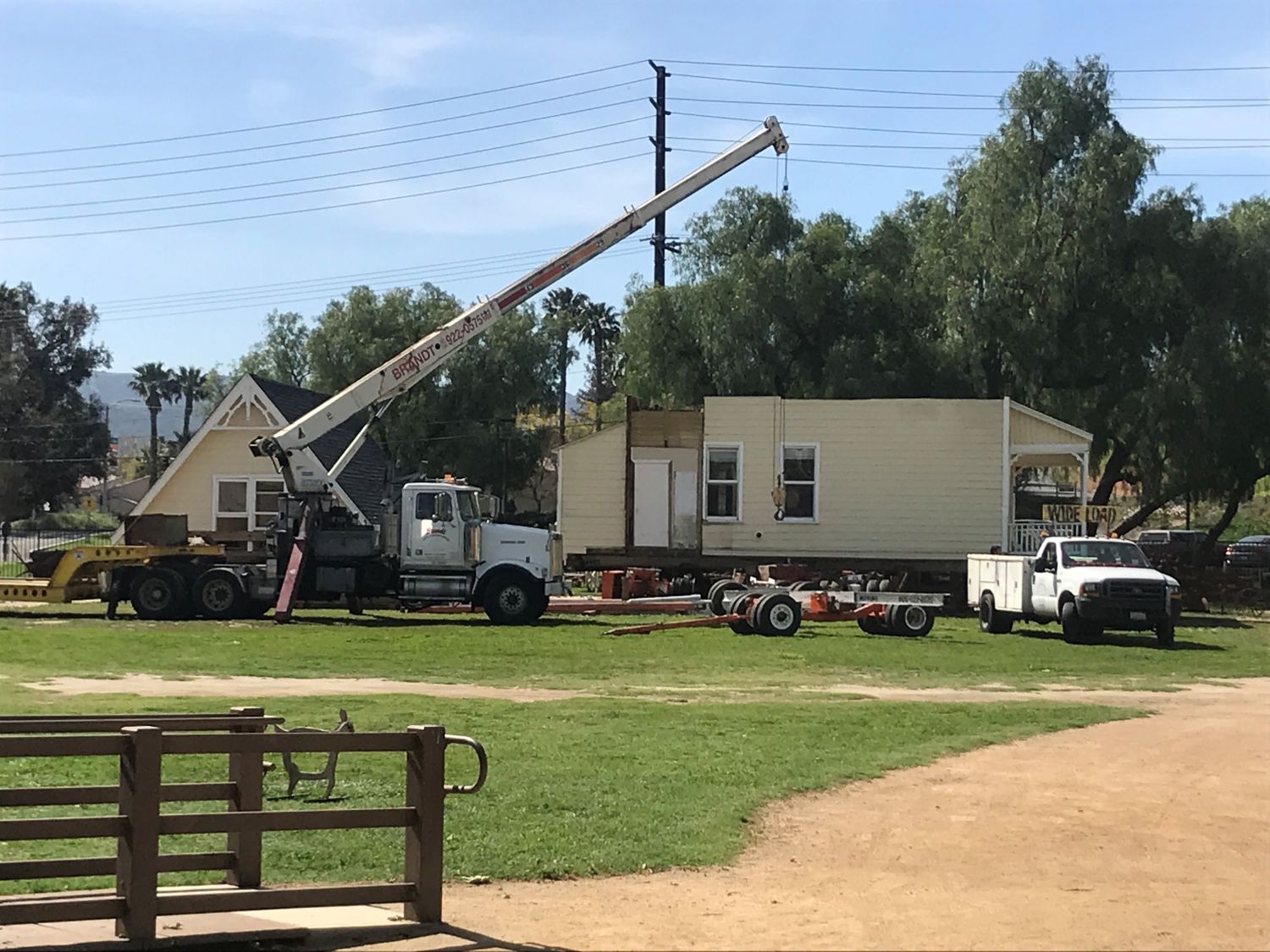 Historic house being relocated using a heavy-duty crane and specialized transport trailer, showcasing oversized freight transportation